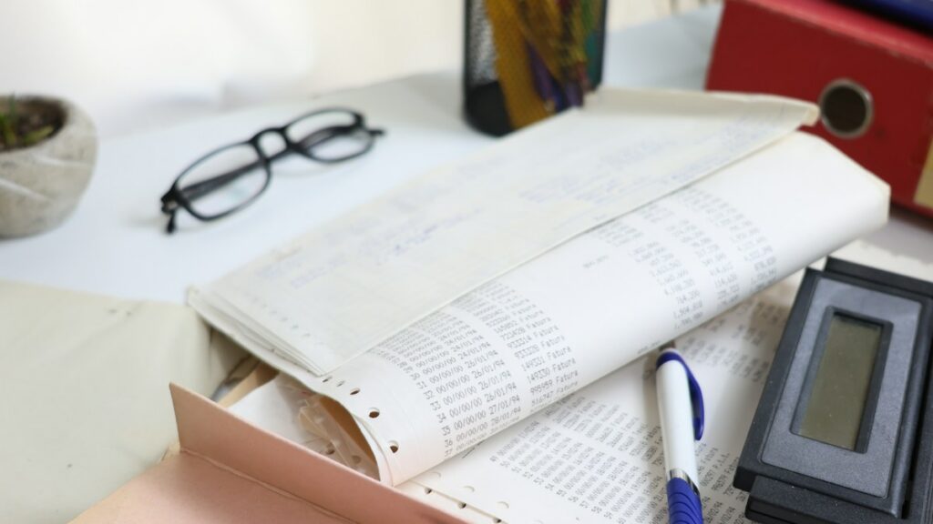 Papers, calculator and office supplies arranged on a desk for reviewing forgotten recurring bills