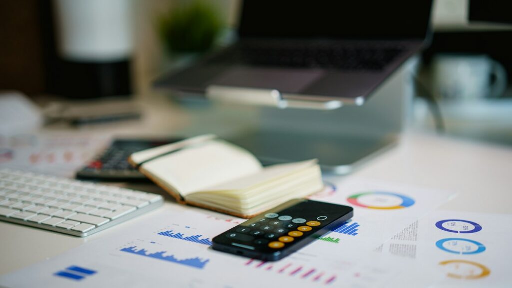 Smartphone and financial charts on a desk showing an expense-analysis workspace
